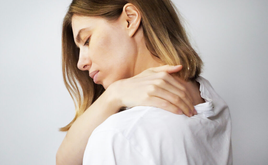 beautiful blonde woman suffering from neck pain while standing in her bedroom in the morning.